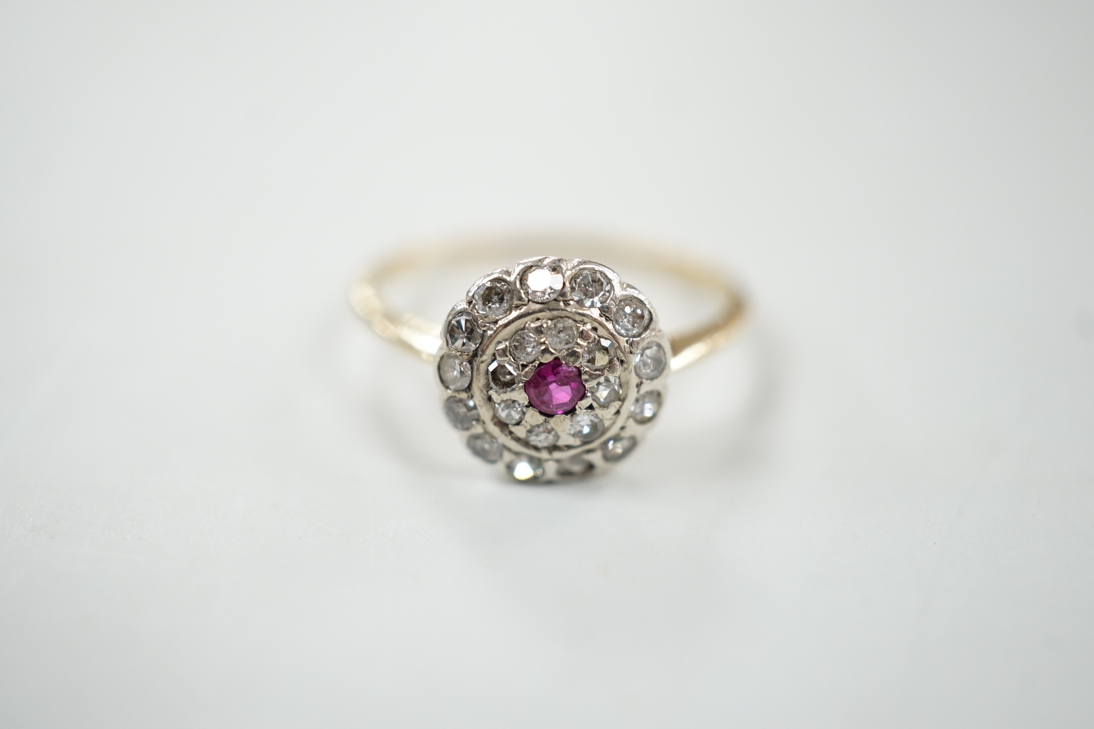 An early to mid 20th century, yellow metal ruby and diamond set target cluster ring, size P, gross weight 2.8 grams.